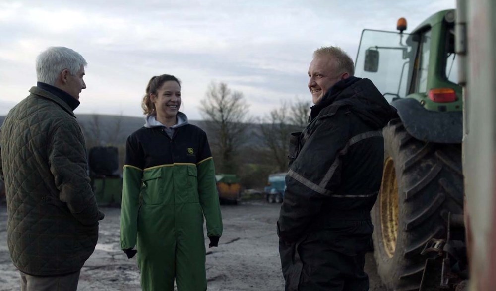 A man and a woman standing next to a tractor.